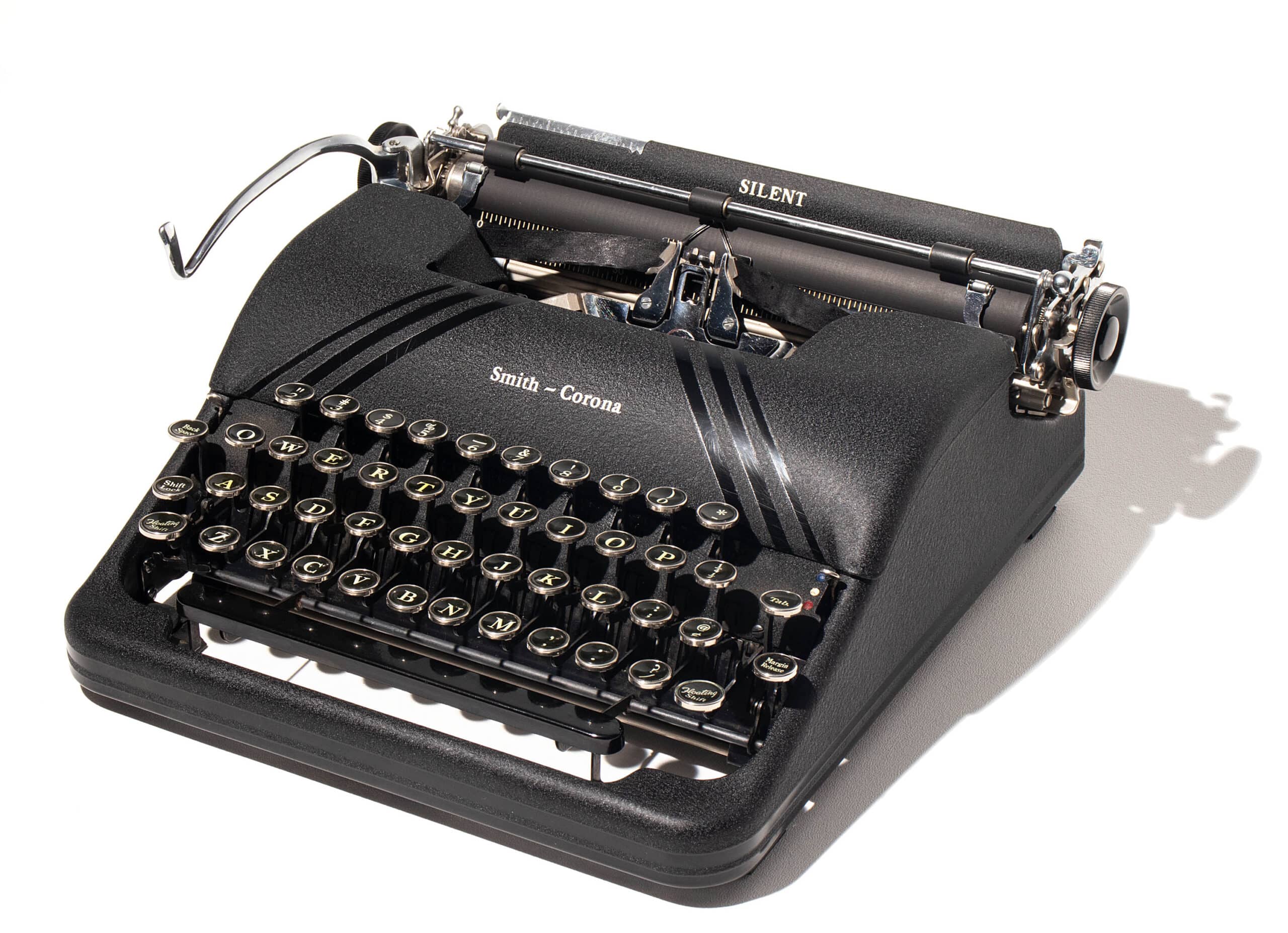 Open black carrying case revealing a vintage Smith-Corona manual typewriter with round keys and metal components visible