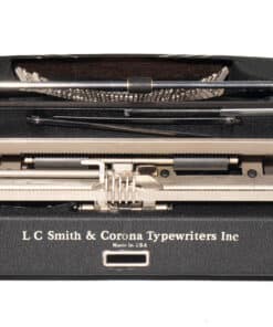 Close-up, top view of a vintage black LC Smith & Corona typewriter showing typebars and carriage area with the brand name visible on the front.