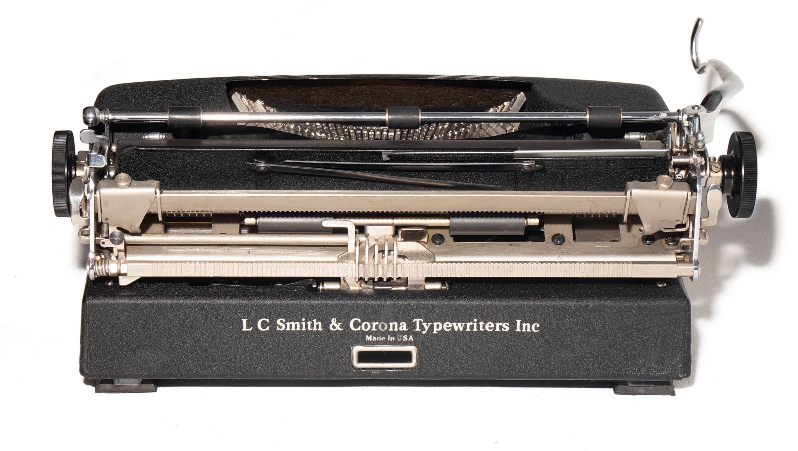 Close-up, top view of a vintage black LC Smith & Corona typewriter showing typebars and carriage area with the brand name visible on the front.