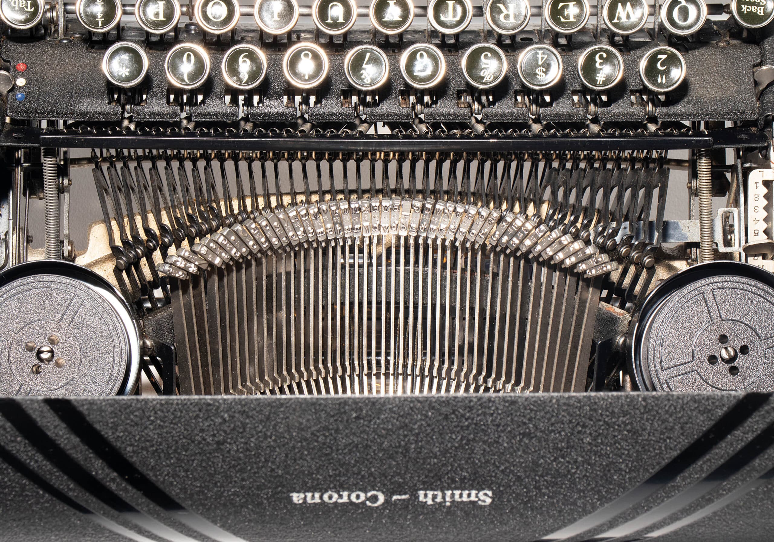 Close-up of a vintage typewriter interior: round metal keys above a row of type hammers and typebars.