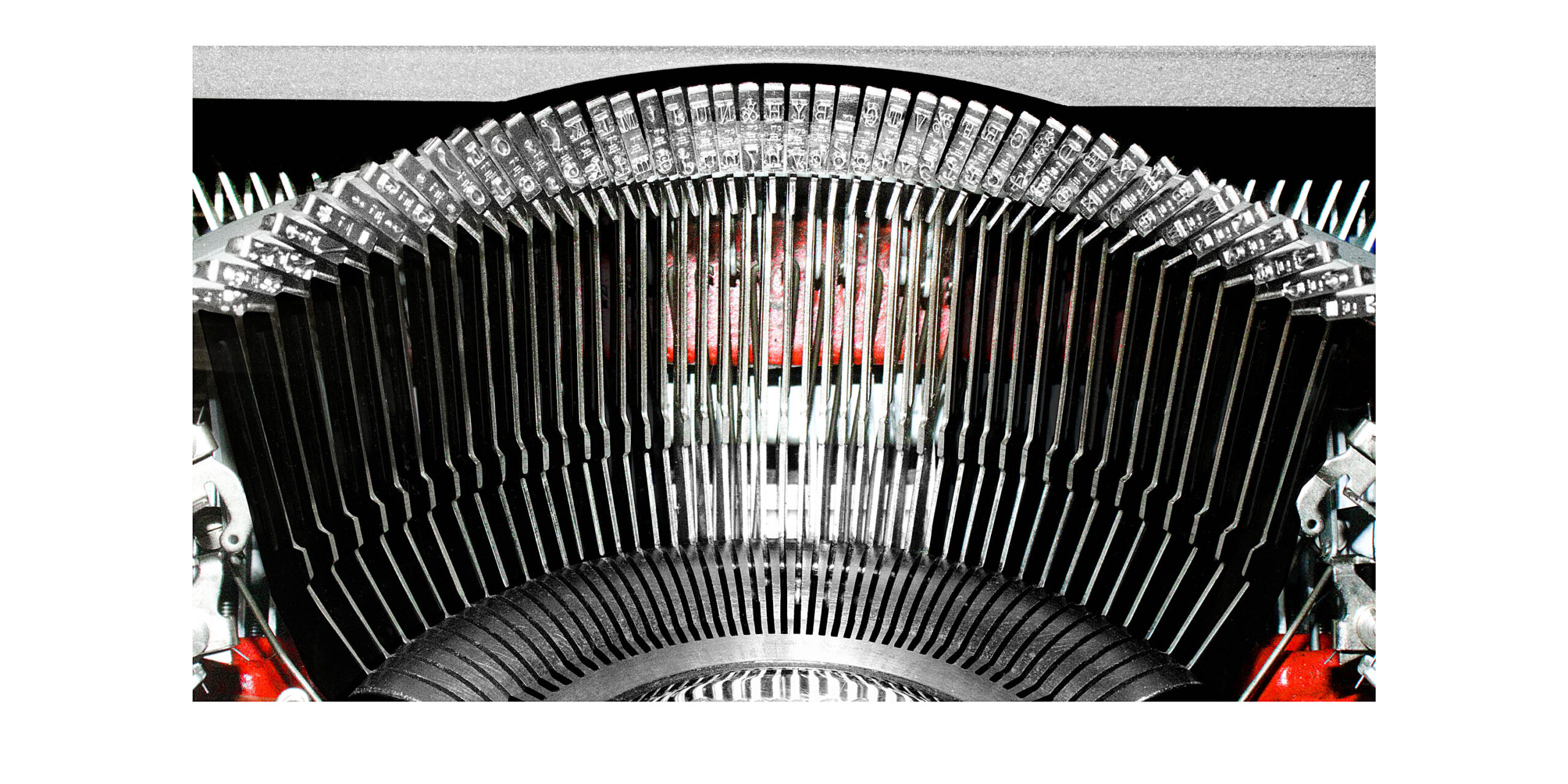 Close-up of a vintage typewriter's curved type bars with a red glow behind the scene.