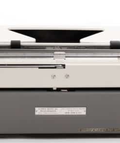 Rear view of a vintage Olympia typewriter with a gray metal body, exposed carriage rails, and a back manufacturer label.