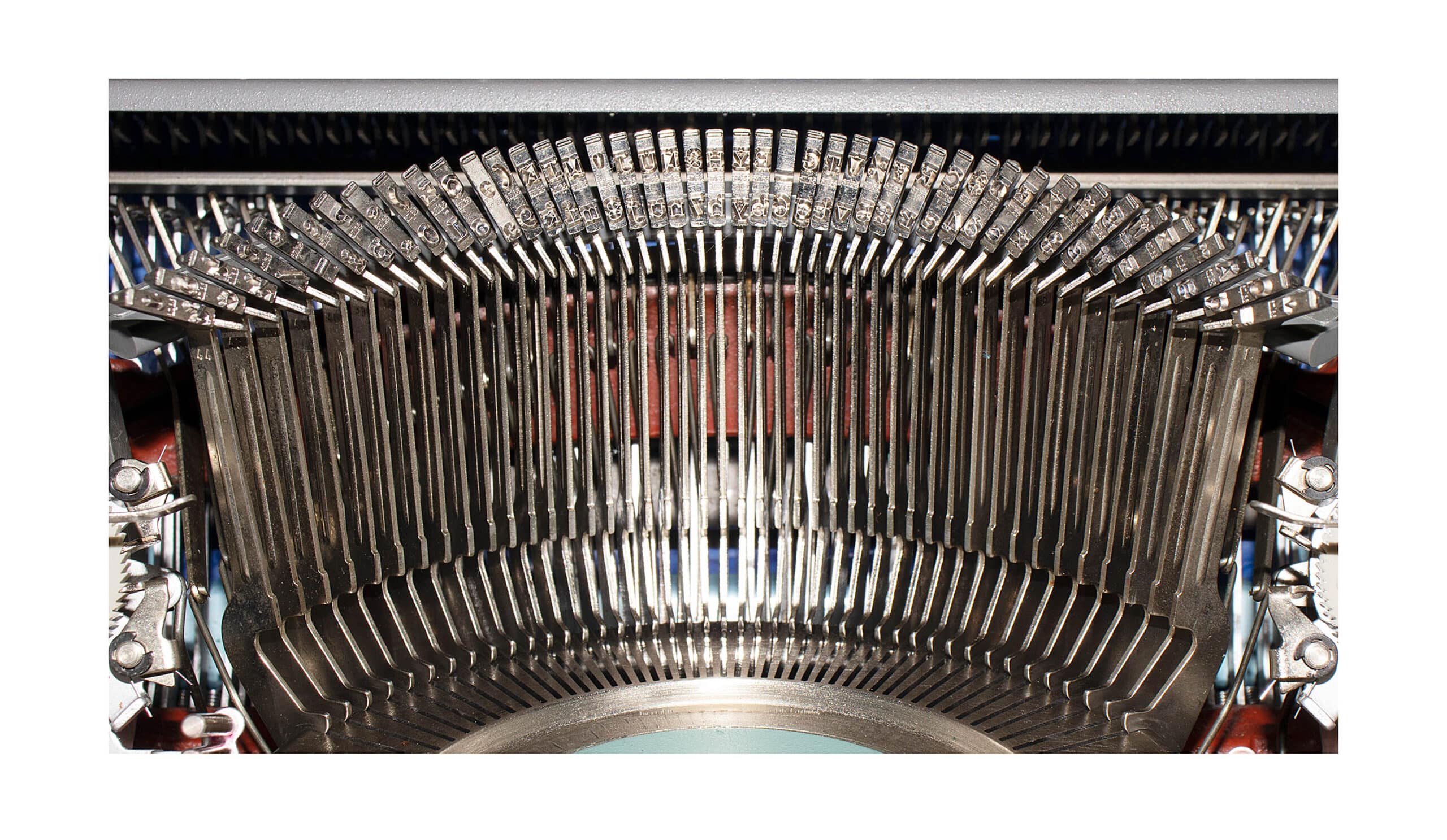 Close-up of a vintage typewriter's type hammers and metal type bars inside the machine, viewed head-on near the platen