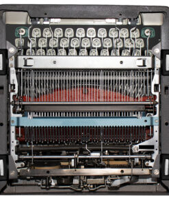 Close-up of a printer's internal print head and ribbon, showing many metal pins and guide rods.