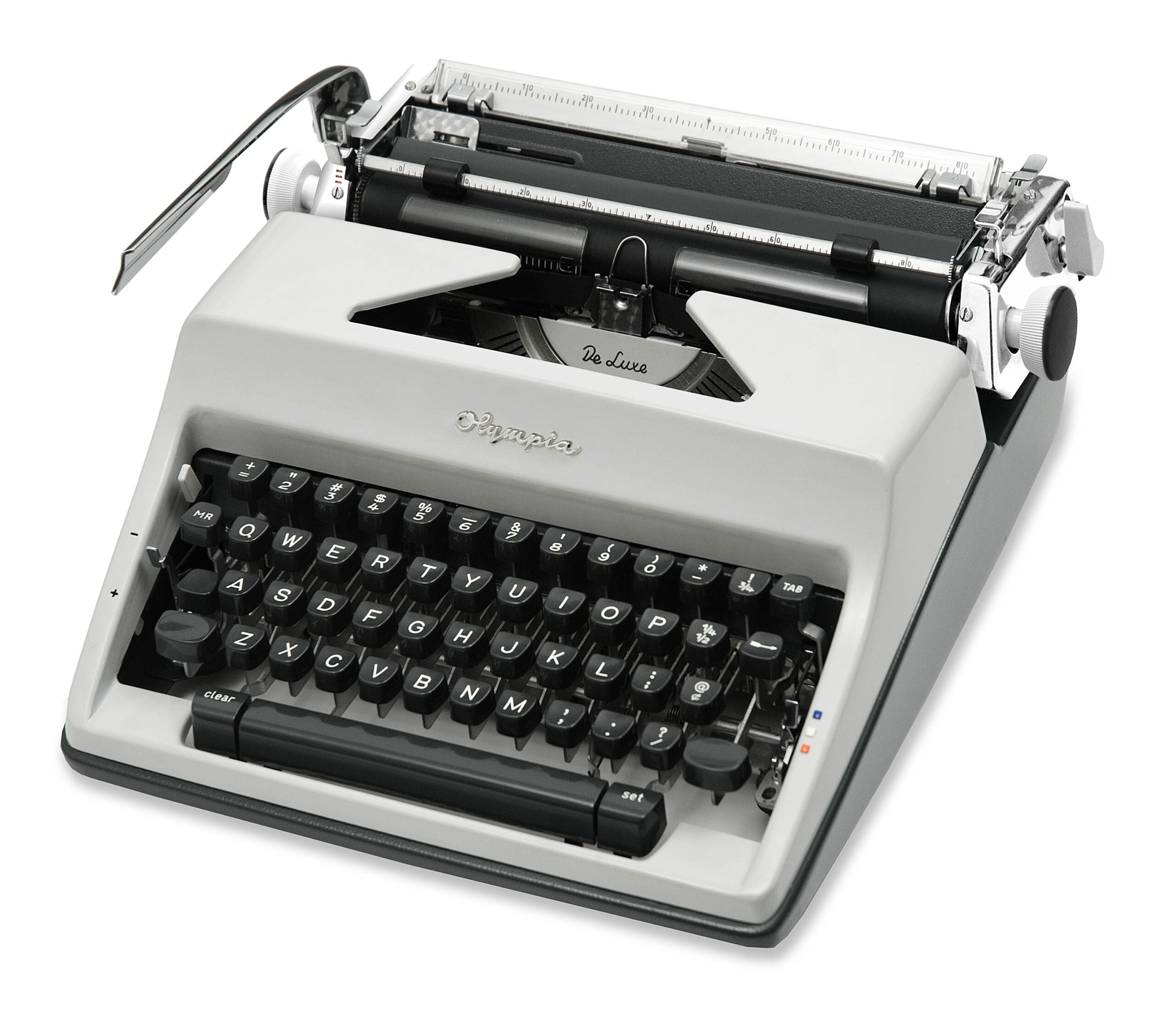 Close-up of an old Olympia De Luxe typewriter, showing the gray body, black keys, and visible carriage with type bars and a silver return lever.