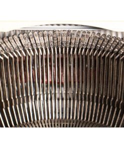 Close-up of metal typewriter typebars with stamped letters arranged in a curved row beneath the carriage.
