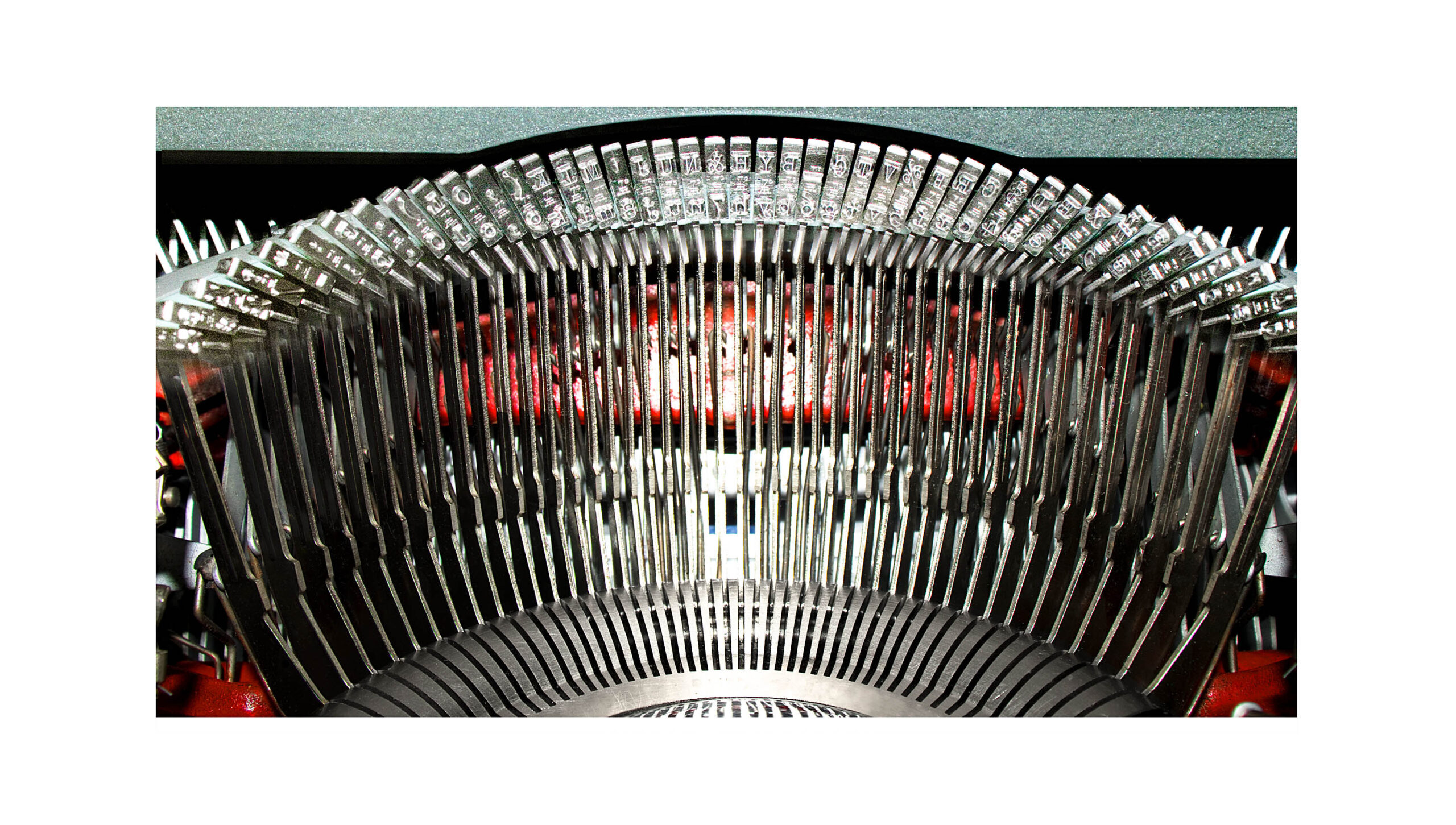 Close-up of a vintage typewriter's metal typebars forming an arc above the platen.