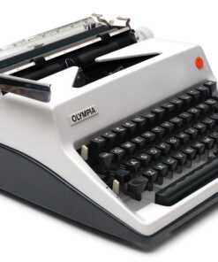 Olympia manual typewriter with black keys on a light gray body, photographed at an angle.