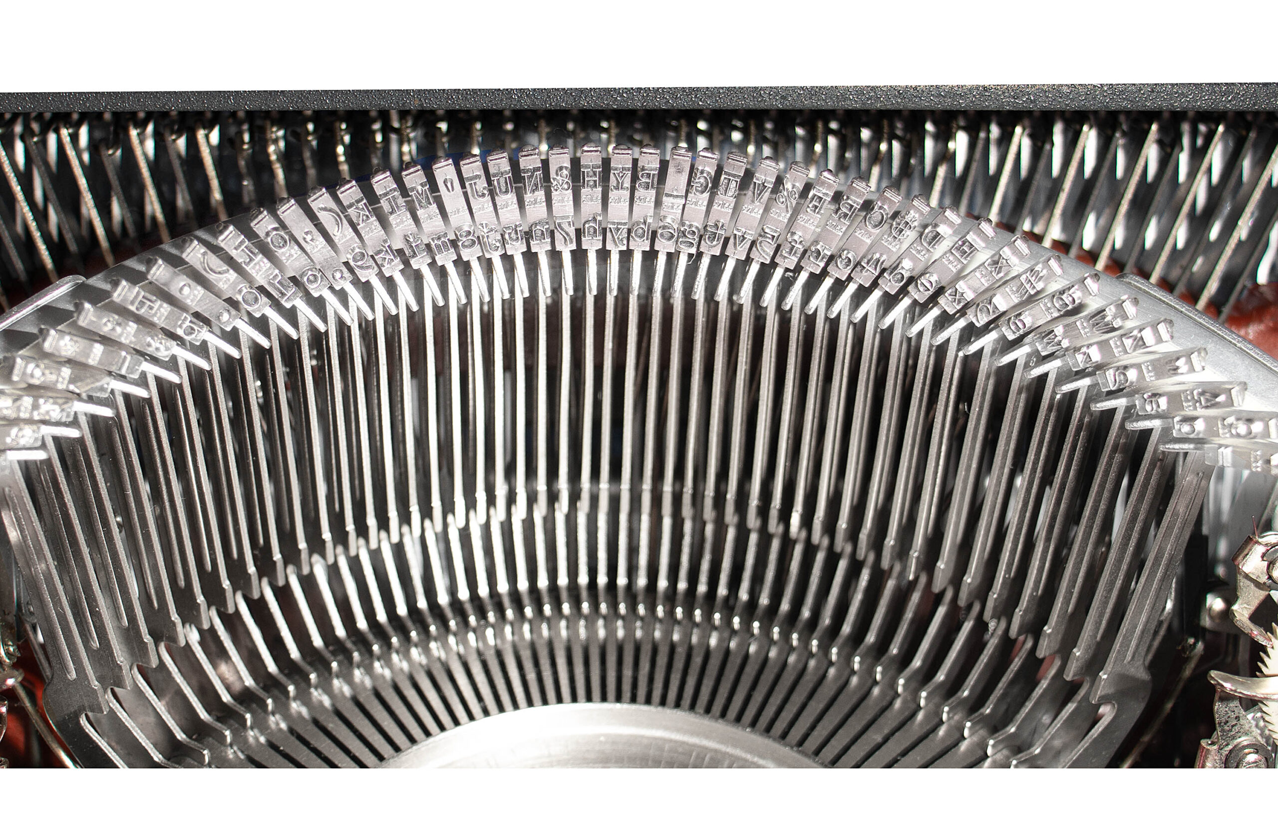 Close-up of a vintage typewriter's typebars fanning out in a circle.