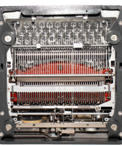 Close-up of a vintage typewriter’s inner mechanism with typebars and ribbon visible inside the frame.