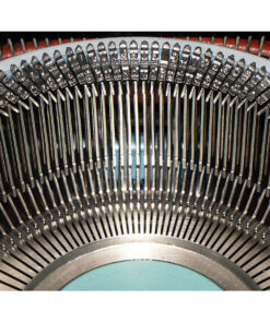 Close-up of a vintage typewriter's curved row of metal type slugs and type bars at the core of the mechanism.