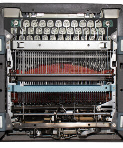 Close-up interior of a vintage printing/punching device showing rows of pins and metal levers.