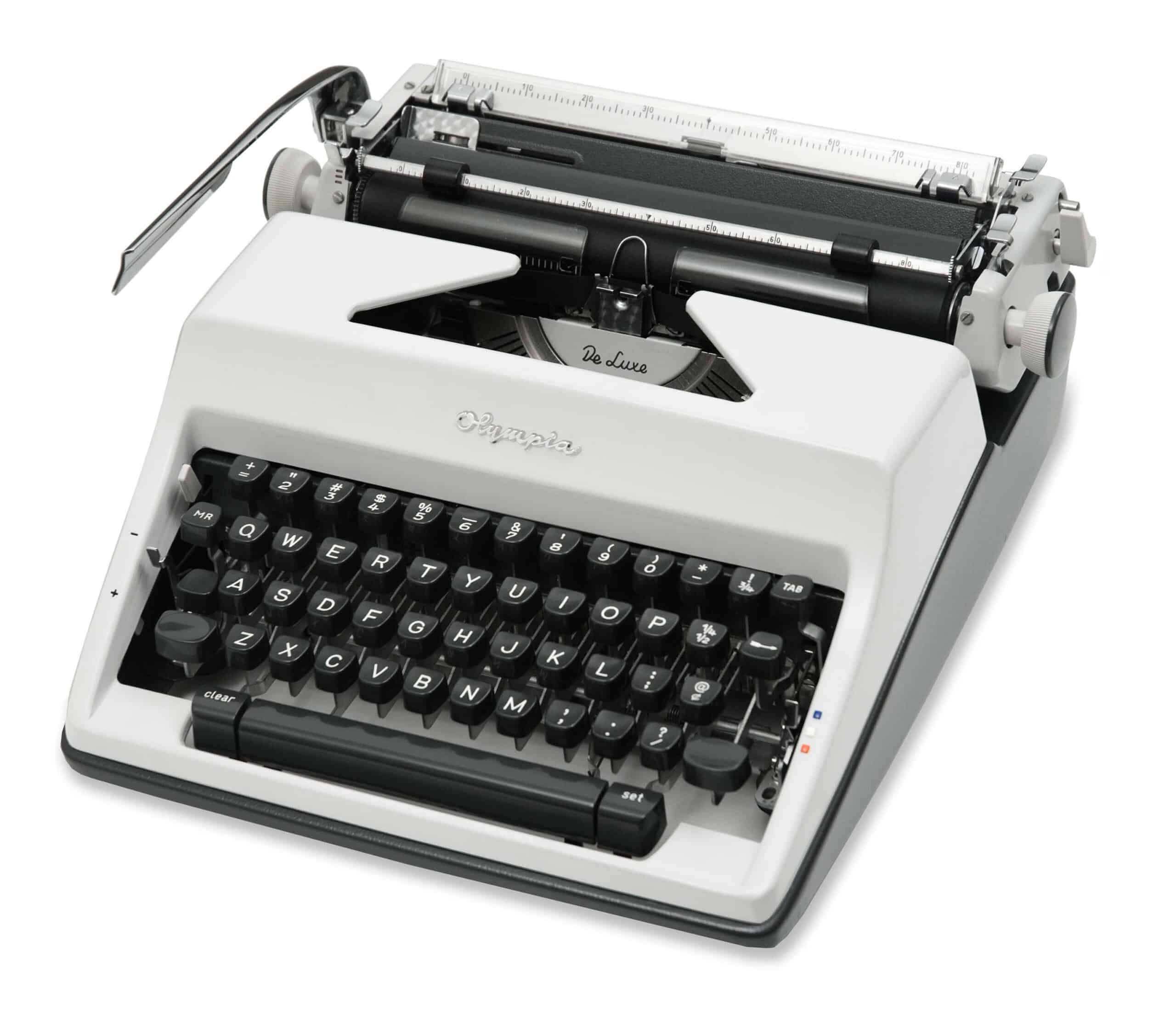 Vintage manual typewriter with white casing and black keys, showing the carriage and ruler on top.