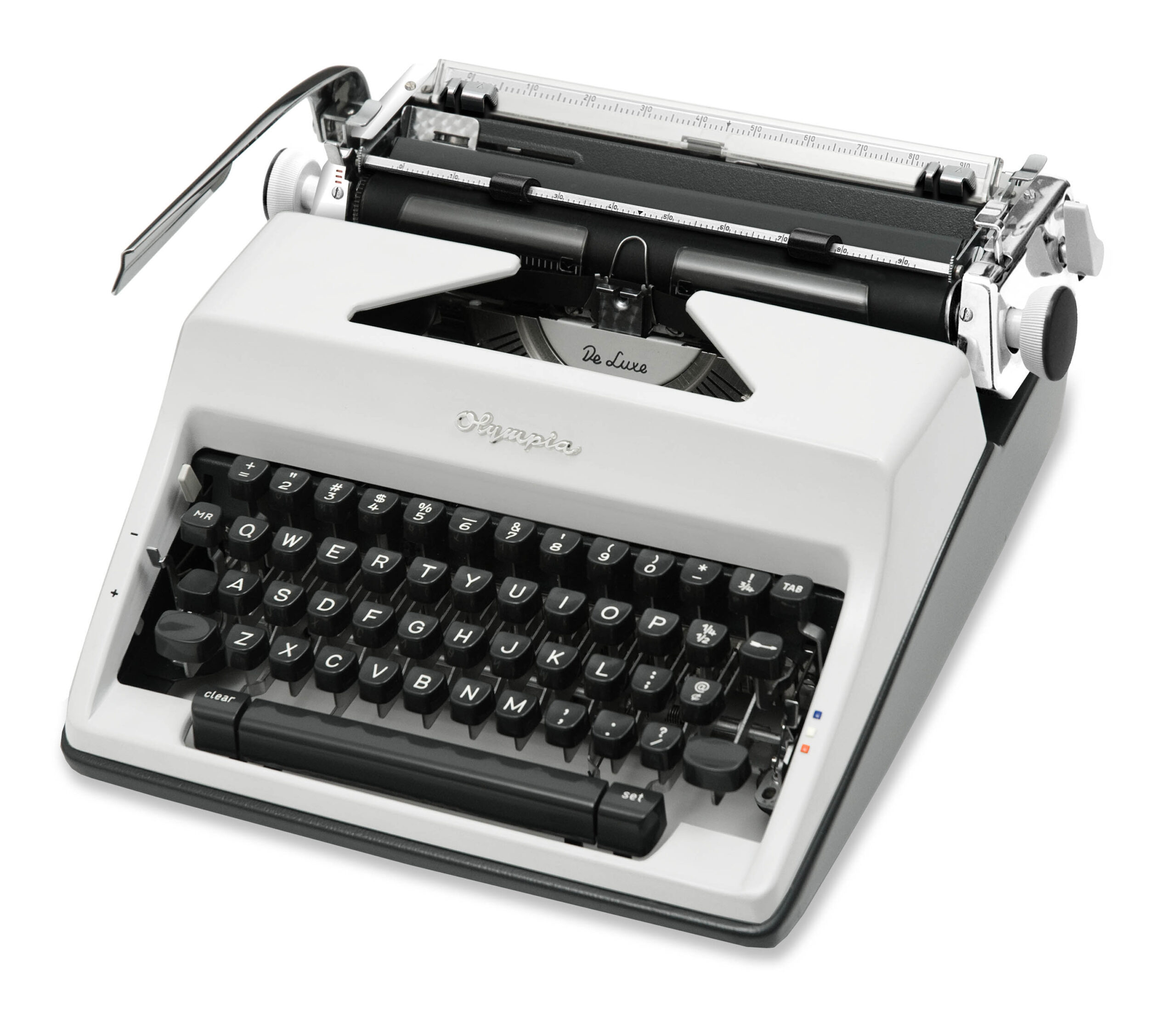 Vintage white Olympia De Luxe typewriter seen from a top-left angle, showing the keyboard and type mechanism.