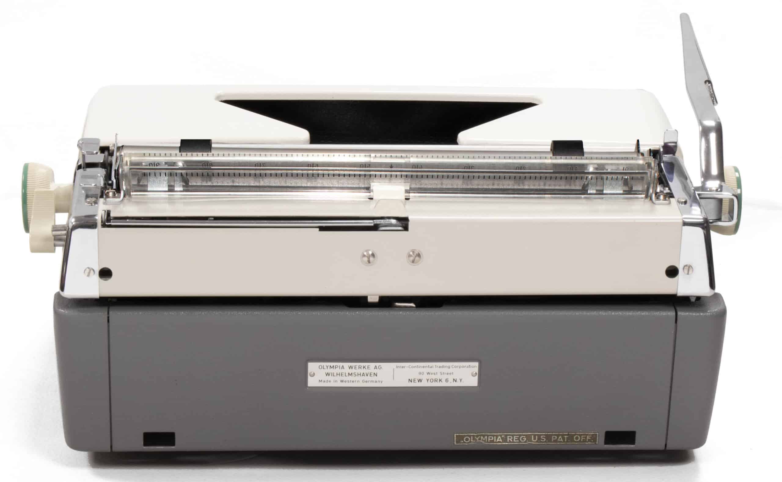 Front view of a vintage manual typewriter with a gray body and metal carriage, keys not visible.