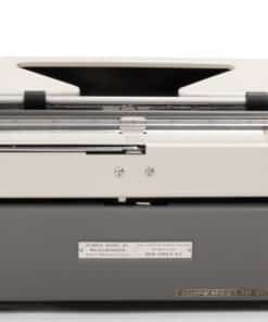 Front view of a vintage Olympia typewriter with a cream top and gray base, showing metal carriage and levers