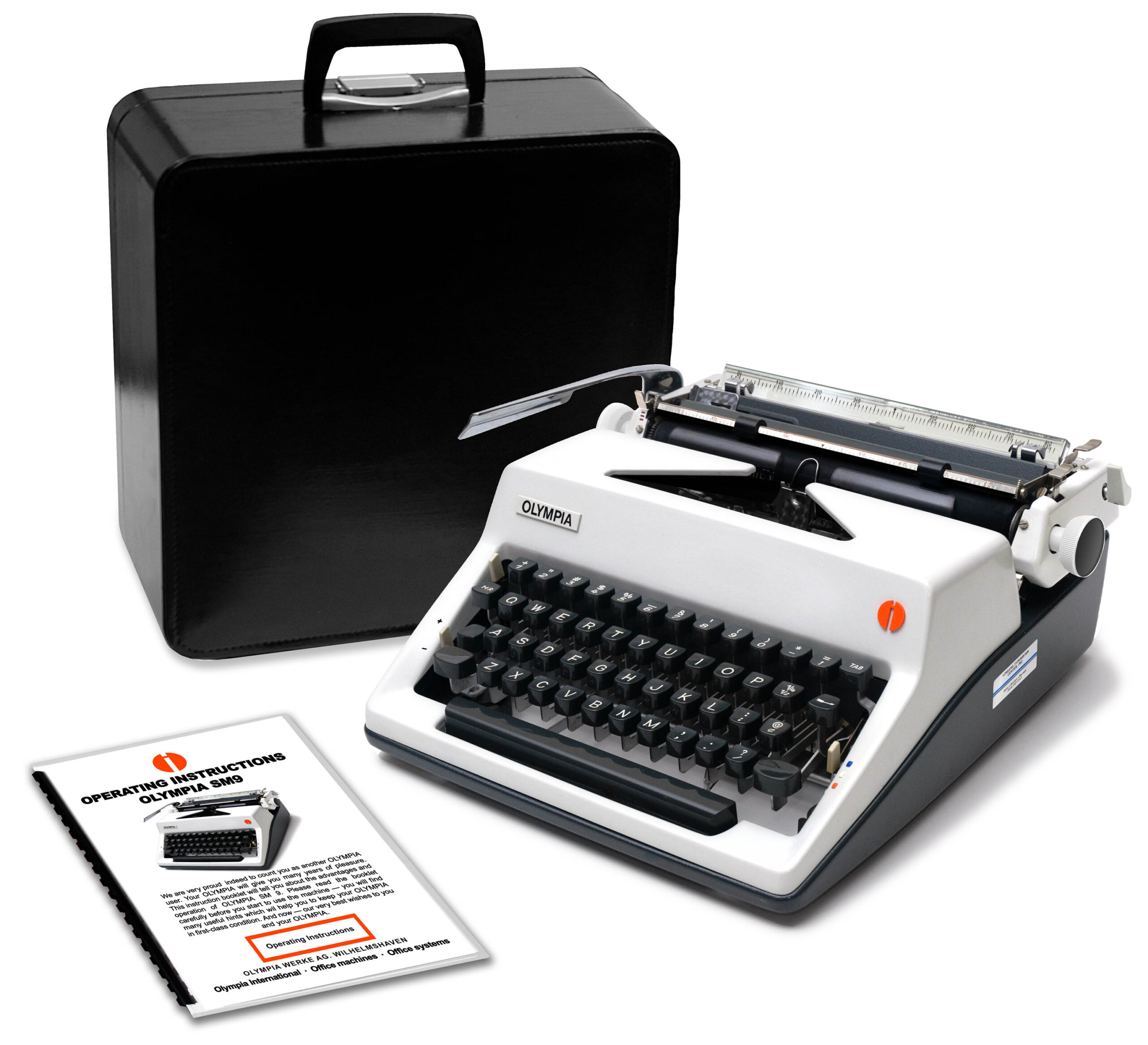 Olympia SM9 manual typewriter in front of a black carrying case with instruction booklets nearby.