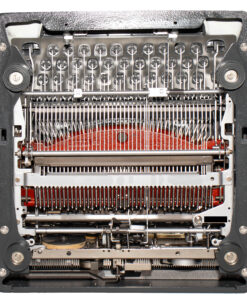 Close-up view of a vintage typewriter's inner mechanism: typebars, ribbon path, and metal levers visible inside the frame.