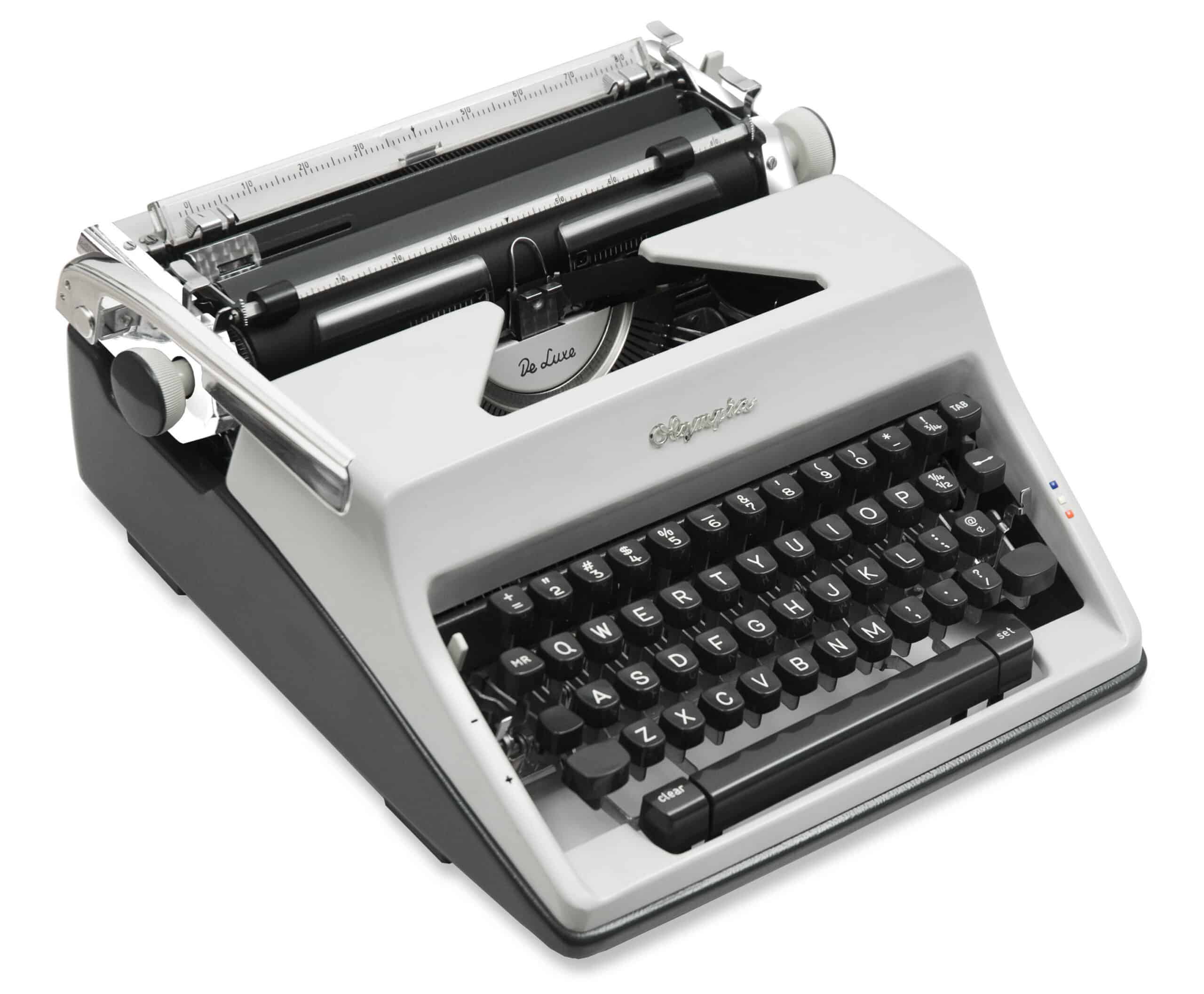 Close-up of a vintage gray typewriter, showing the carriage, typebars, and black round keys with white letters.