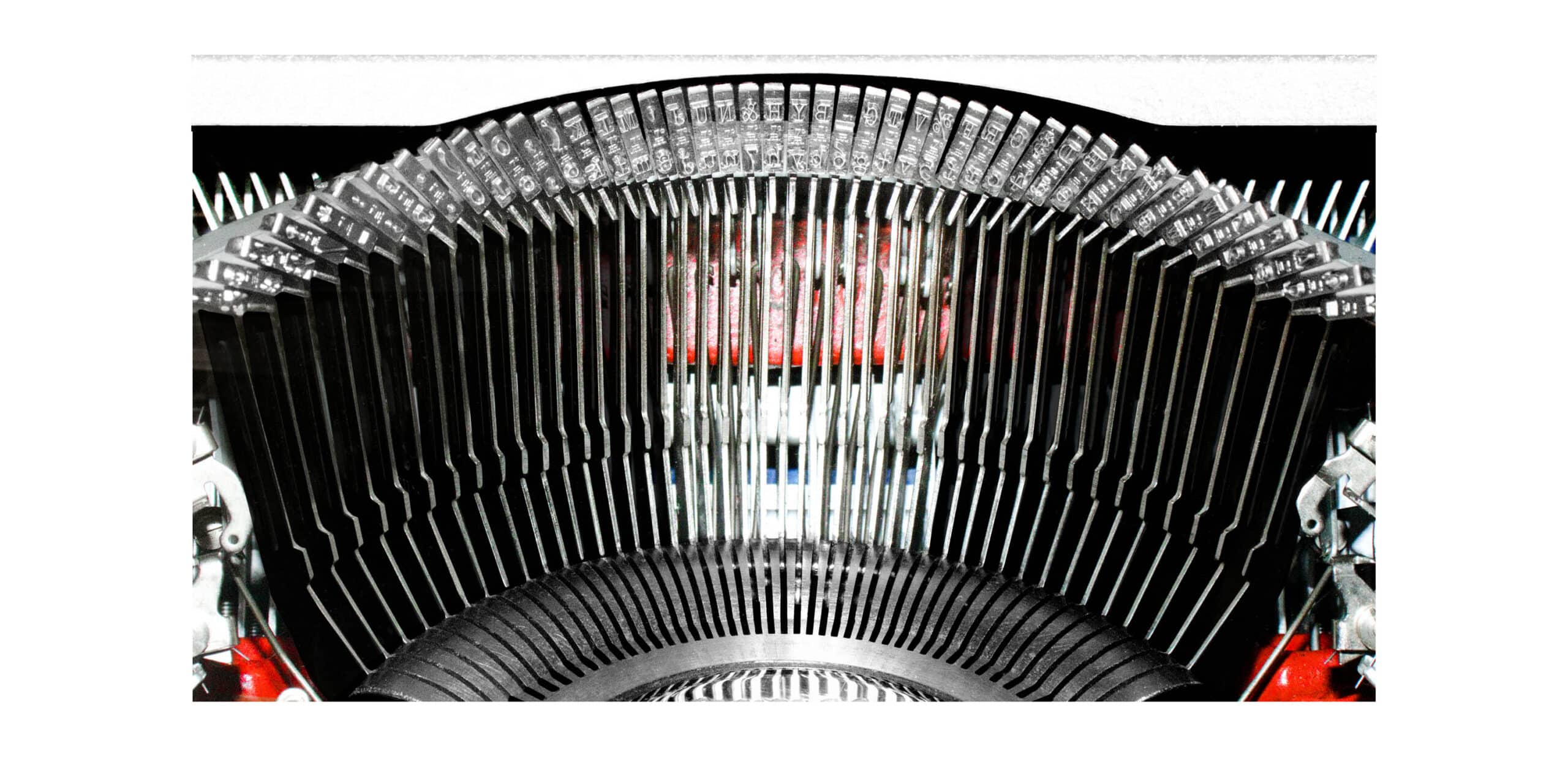 Close-up of a vintage typewriter’s typebars arching over the center platen, showing metal slugs with letters and numbers.