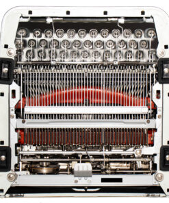 Close-up of a vintage typewriter's inner typebar mechanism with rows of keys and metal levers, red frame visible in the background.
